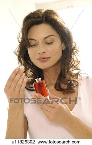 Stock Image - Woman is smelling on a perfum flacon. Fotosearch