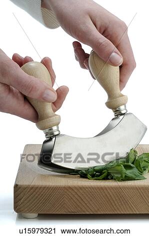 Stock Image - Cutting herbs with a mincing knife. Fotosearch