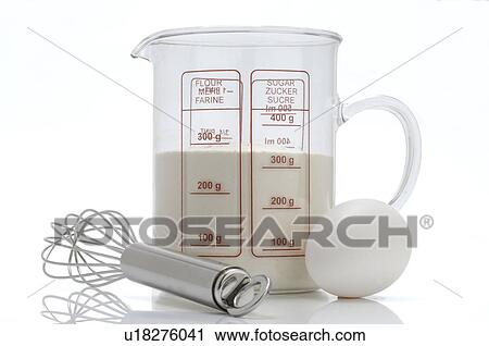 Stock Image - Flour in a measuring jug, whisk and egg. Fotosearch
