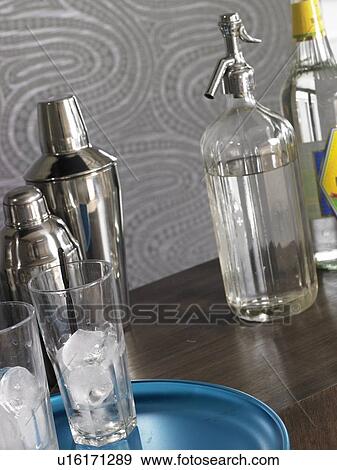 Stock Photo - Cocktail bar: Shaker, soda and glasses with ice cubes. Fotosearch