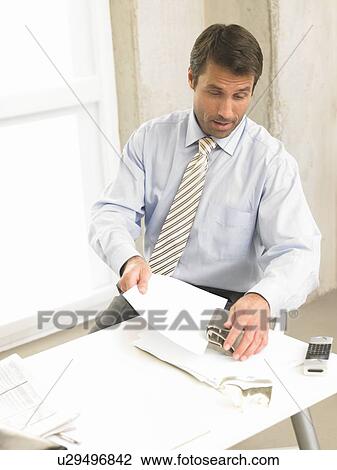 Stock Image - Business man is punching documents. Fotosearch