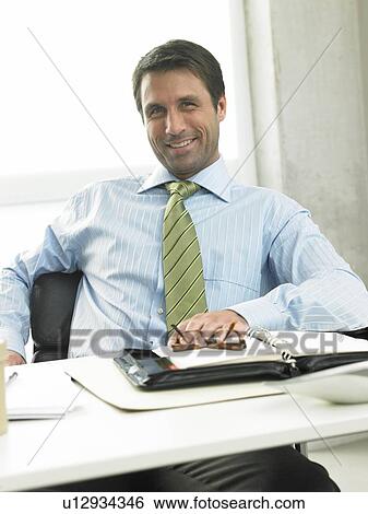 Stock Photograph - Business man on his desk. Fotosearch