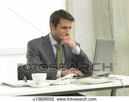 Business man on his desk working with his laptop View Large Photo Image Stock Image - Business man on his desk working with his laptop. Fotosearch