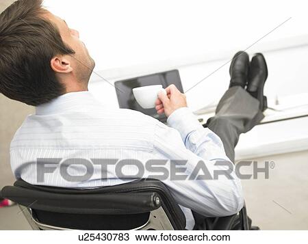 Business man with feet on desk is drinking coffee View Large Photo Image Stock Image - Business man with feet on desk is drinking coffee. Fotosearch
