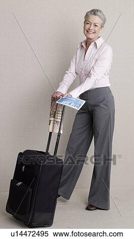 Stock Photography - Senior adult with a bag, newspaper and flight ticket. Fotosearch