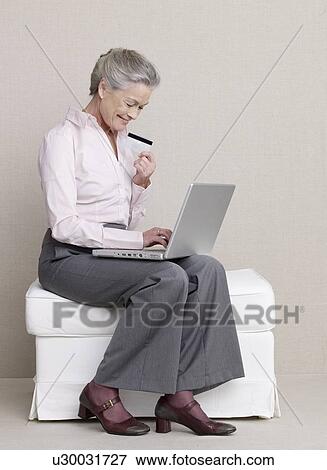 Stock Photo - Senior adult with laptop and credit card. Fotosearch