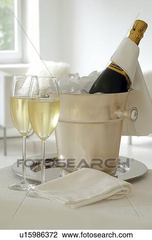 Stock Image - Champagne bottle in an ice bucket and two champagne glasses. Fotosearch