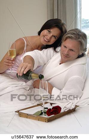 Couple in bed drinking sparkling wine View Large Photo Image Stock Photo - Couple in bed drinking sparkling wine. Fotosearch