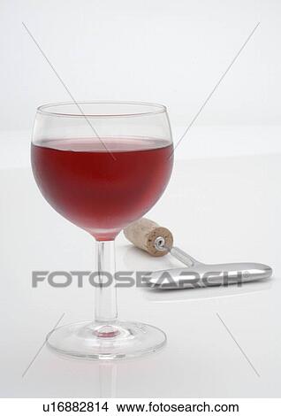 Picture - Glass of red wine and a corkscrew. Fotosearch