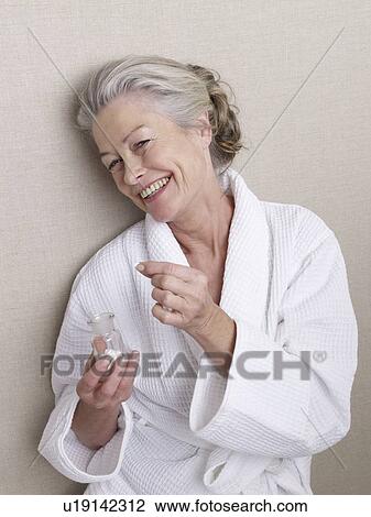 Senior adult in bathrobe holding glass of pills View Large Photo Image Stock Image - Senior adult in bathrobe holding glass of pills. Fotosearch