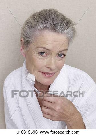 Stock Image - Senior adult in bathrobe using brush. Fotosearch