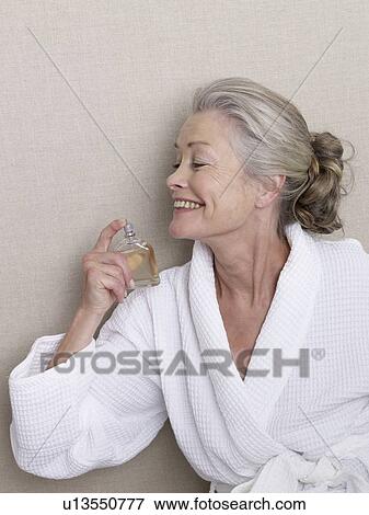 Stock Photo - Senior adult in bathrobe with perfume. Fotosearch