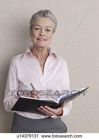 Stock Image - Senior adult in business clothing holding datebook. Fotosearch