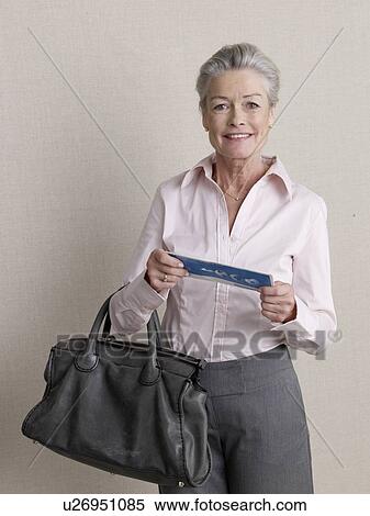 Stock Photography - Senior adult in business clothing holding air ticket. Fotosearch
