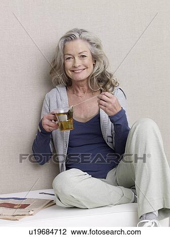 Stock Image - Senior adult in sports clothing holding glass of tea. Fotosearch