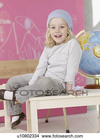 Blond girl wearing a headscarf sitting on the table next to globe View Large Photo Image Picture - Blond girl wearing a headscarf sitting on the table next to globe. Fotosearch