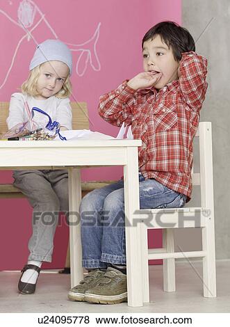 Girl and boy sitting at the table View Large Photo Image Stock Photo - Girl and boy sitting at the table. Fotosearch