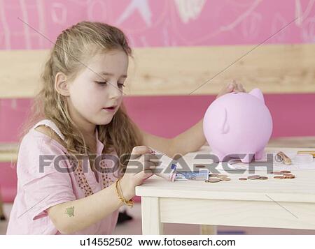Girl is putting money in a piggy bank View Large Photo Image Stock Image - Girl is putting money in a piggy bank. Fotosearch