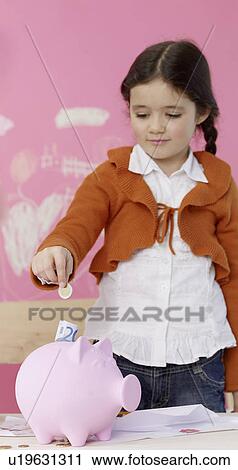 Girl is putting money in a piggy bank View Large Photo Image Stock Image - Girl is putting money in a piggy bank. Fotosearch