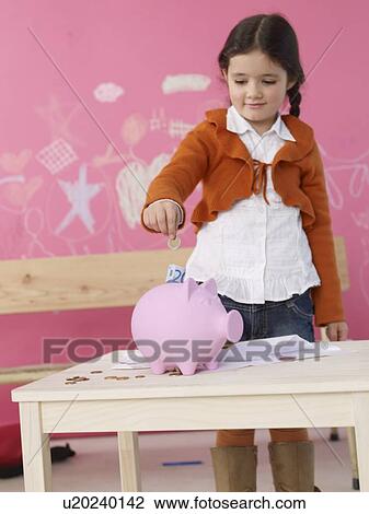 Girl is putting money in a piggy bank View Large Photo Image Stock Image - Girl is putting money in a piggy bank. Fotosearch