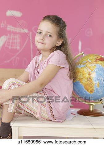 Stock Photograph - Girl sitting next to a globe. Fotosearch