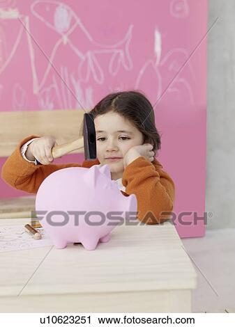 Stock Image - Girl with hammer and piggy bank. Fotosearch