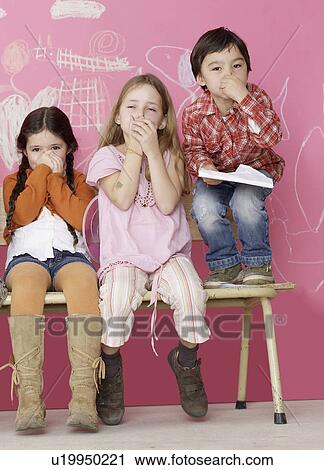 Stock Image - Three children keeping their noses shut. Fotosearch