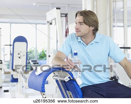 Stock Photograph - Man in health club holding a bottle of water. Fotosearch