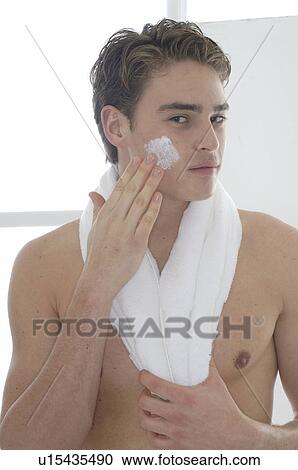 Stock Image - Man is applieing creme on his face. Fotosearch