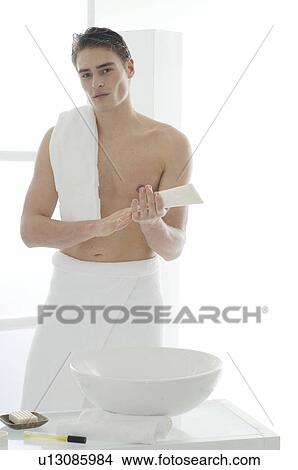 Picture - Man standing in front of a washbowl with body lotion. Fotosearch