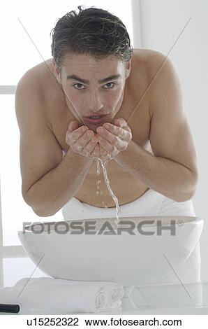 Man standing in front of a washbowl washing his face View Large Photo Image Stock Image - Man standing in front of a washbowl washing his face. Fotosearch