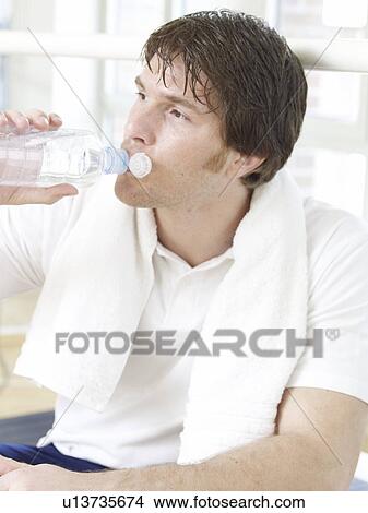 Man with a towel around his neck is drinking water View Large Photo Image Picture - Man with a towel around his neck is drinking water. Fotosearch