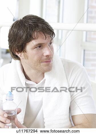 Picture - Man with a towel around his neck holding a bottle of water. Fotosearch