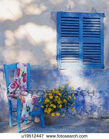 Stock Photo - Blue chair in front of weathered blue wall with shutter. Fotosearch