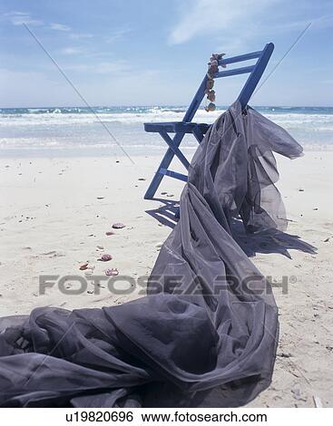 Stock Photograph - Chair and blue cloth on the beach. Fotosearch