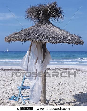 On the beach: parasol made of straw and a chair View Large Photo Image Stock Image - On the beach: parasol made of straw and a chair. Fotosearch
