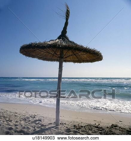 Stock Image - Parasol made of straw on the beach. Fotosearch