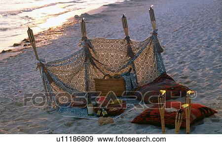Stock Photo - Twilight on the beach: windbreak and torches. Fotosearch