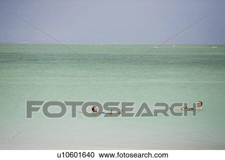 Stock Image - Two men swimming in Dead Sea. Fotosearch