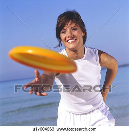 Stock Image - Woman in sportswear playing with frisbee. Fotosearch