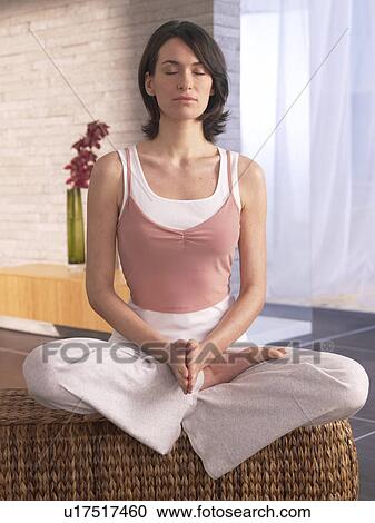 Stock Image - Woman sitting cross-legged doing yoga exercise. Fotosearch