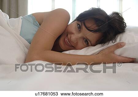 Stock Image - Smiling woman in her bed. Fotosearch