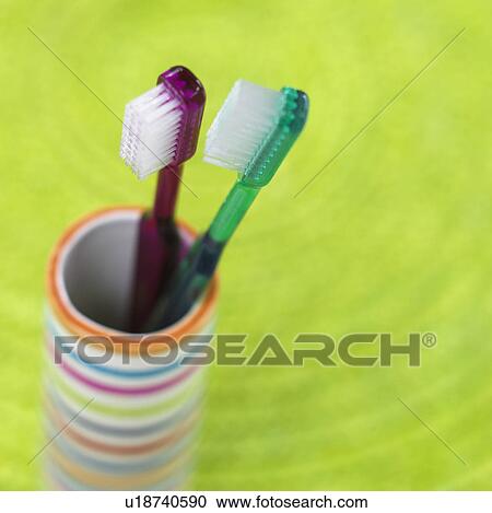 Stock Image - two toothbrushes in a striped beaker. Fotosearch
