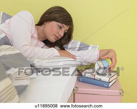 Woman looking at the alarmclock View Large Photo Image Stock Photo - Woman looking at the alarmclock. Fotosearch