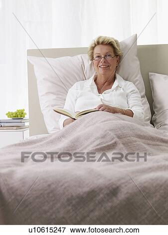 Stock Photo - elderly lady reading in bed. Fotosearch