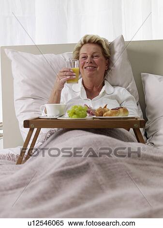 Stock Photography - senior lady having breakfast in bed. Fotosearch