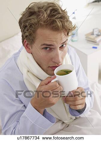 Picture - young man having a cup of herb tea. Fotosearch