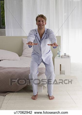 Stock Image - young man in blue pyjamas doing morning sports. Fotosearch