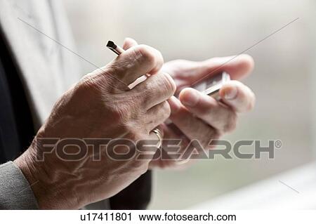 Stock Image - Close-up of human hands holding mobile phone with touchpad. Fotosearch
