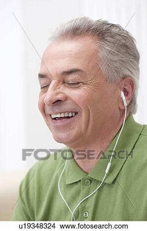 Picture - Domestic Life, a senior man listening to music with eyes closed and smiling. Fotosearch
